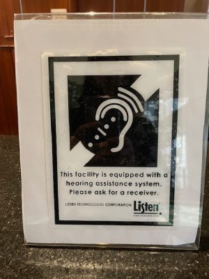 Photo of a sign at the Bushnell reading, "This facility is equipped with a hearing assistance system. Please ask for a receiver."