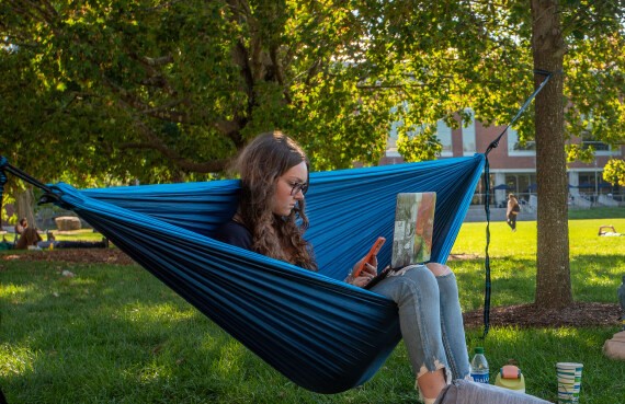 Students studies outside on a hammock