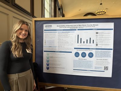 Photo of Sarah in front of poster